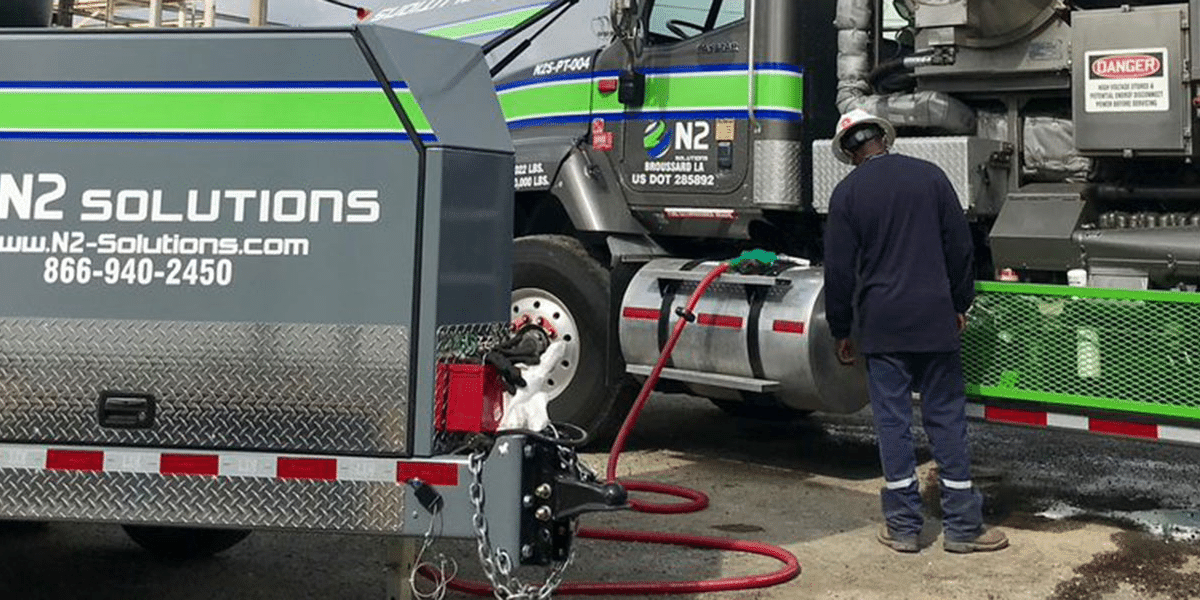 N2 employee wearing a hard hat working on a nitrogen transport truck